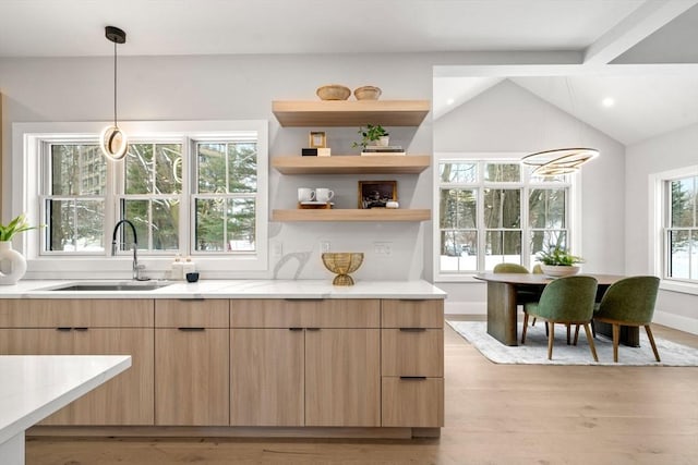 bar with pendant lighting, lofted ceiling, sink, light stone countertops, and light hardwood / wood-style flooring