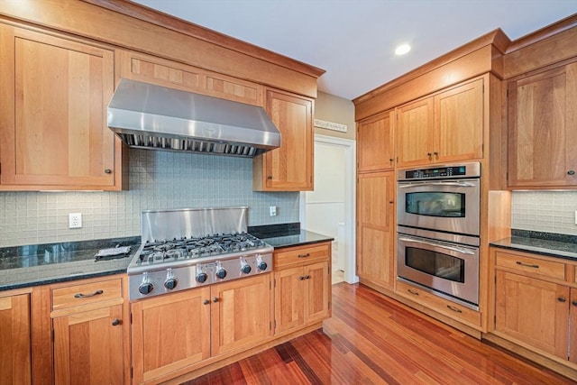 6 Northey Farm Rd, Scituate, MA 02066 - kitchen with wall chimney exhaust hood, appliances with stainless steel finishes, dark wood-style floors, tasteful backsplash, and dark stone countertops