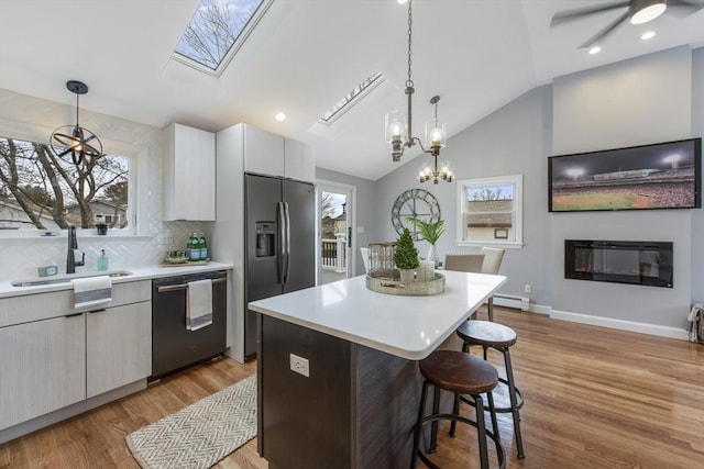 kitchen featuring stainless steel refrigerator with ice dispenser, baseboard heating, a glass covered fireplace, a sink, and dishwasher