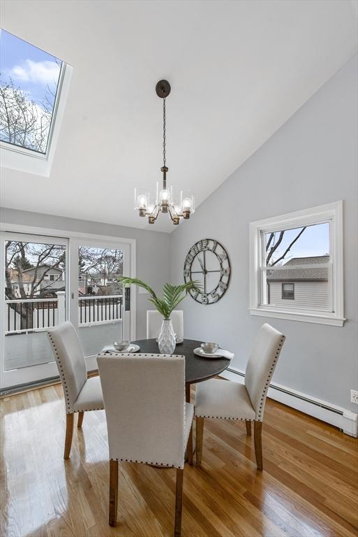 dining room with a baseboard heating unit, lofted ceiling, a chandelier, and wood finished floors