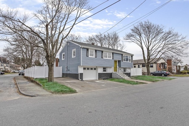 view of front of house featuring a garage, a residential view, fence, and aphalt driveway