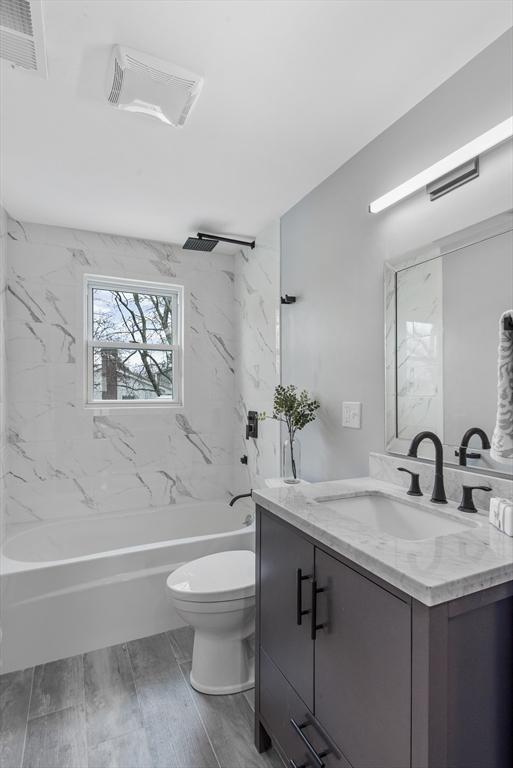 full bath featuring visible vents, toilet, wood tiled floor, vanity, and shower / tub combination