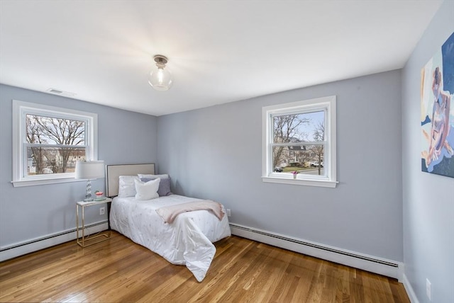 bedroom with multiple windows, baseboard heating, and visible vents