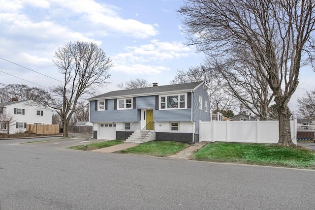 bi-level home with a garage, a chimney, and fence