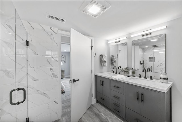 bathroom with a marble finish shower, visible vents, and a sink