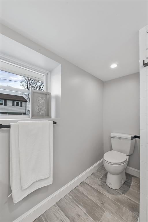 bathroom featuring wood finish floors, baseboards, and toilet