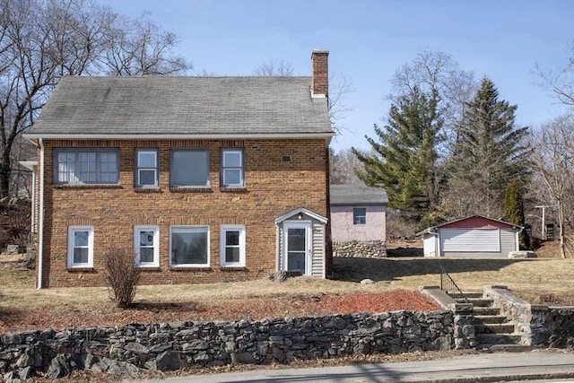 colonial house with an outbuilding, brick siding, and a chimney