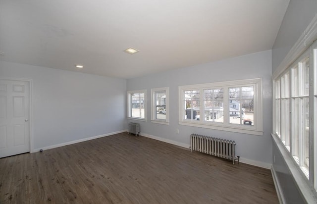 unfurnished room featuring baseboards, radiator, and wood finished floors