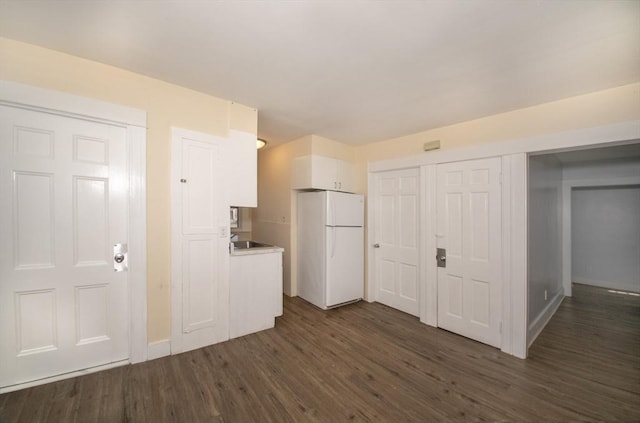 kitchen featuring a sink, dark wood-style floors, white cabinetry, freestanding refrigerator, and light countertops