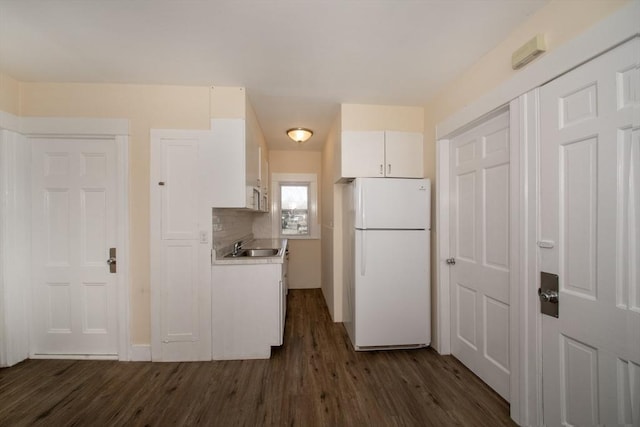 kitchen featuring dark wood-style floors, freestanding refrigerator, light countertops, white cabinetry, and tasteful backsplash