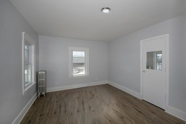 unfurnished room with radiator heating unit, baseboards, and wood finished floors