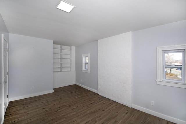 empty room featuring baseboards and dark wood-style flooring