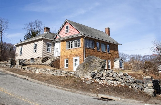 view of front facade featuring brick siding and a chimney