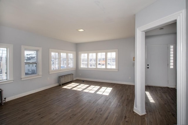 empty room featuring baseboards, radiator, and dark wood finished floors