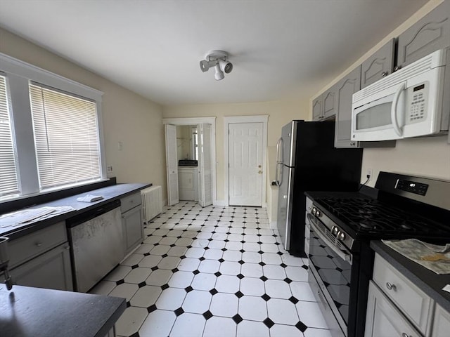 589-591 Washington St, Brookline, MA 02446 - kitchen featuring appliances with stainless steel finishes, light flooring, dark countertops, and washer / clothes dryer