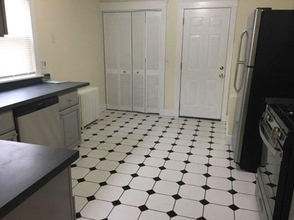 589-591 Washington St, Brookline, MA 02446 - kitchen featuring stainless steel appliances, dark countertops, radiator, and light flooring
