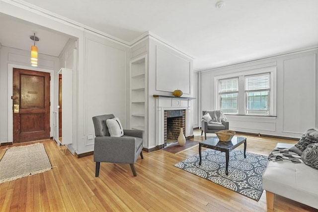 3 Arlington St Unit 7, Cambridge, MA 02140 - living room featuring a decorative wall, ornamental molding, light wood-type flooring, a brick fireplace, and built in features