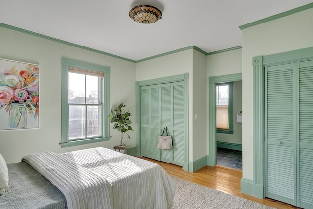 bedroom featuring light wood-type flooring, multiple windows, and ornamental molding