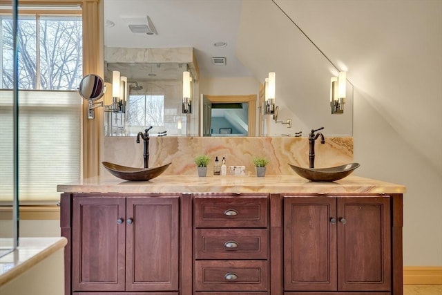 bathroom featuring a shower with shower door and vanity