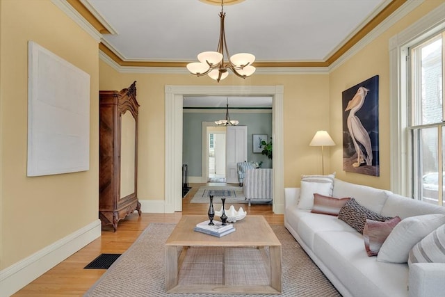 living room with a chandelier, light hardwood / wood-style floors, and ornamental molding