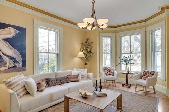 living room featuring a healthy amount of sunlight, crown molding, hardwood / wood-style flooring, and an inviting chandelier