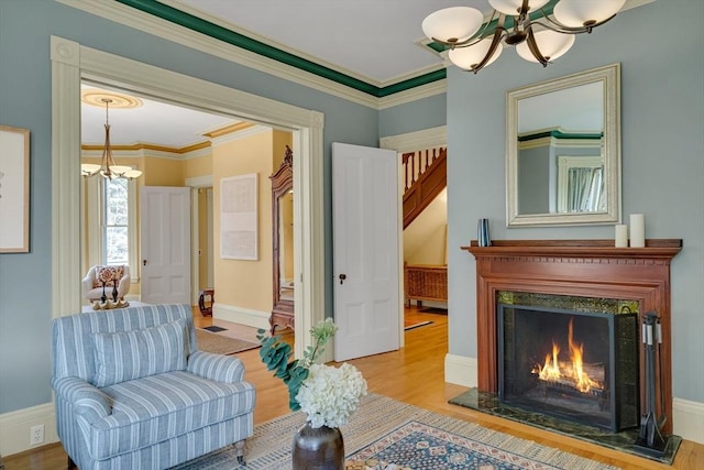 living area featuring an inviting chandelier, ornamental molding, and light hardwood / wood-style floors