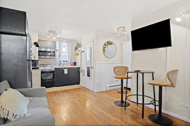 kitchen with baseboard heating, appliances with stainless steel finishes, sink, light wood-type flooring, and decorative backsplash