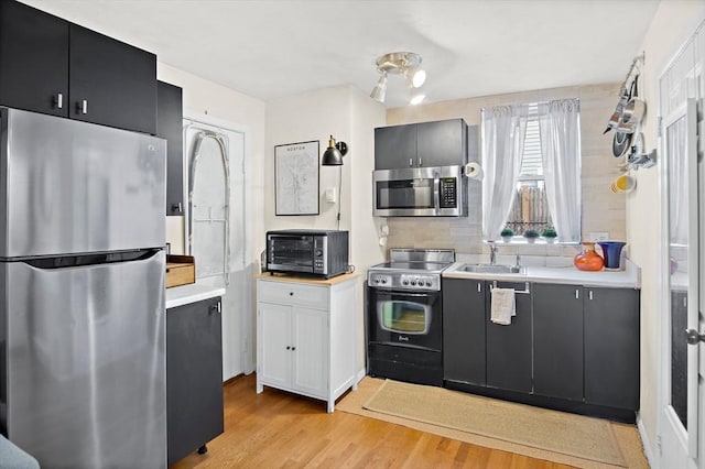 kitchen with light wood-type flooring, stainless steel appliances, decorative backsplash, and sink