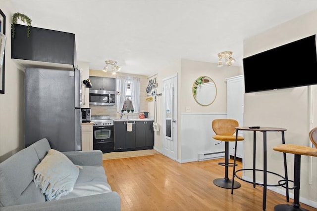 living room with light wood-type flooring, a baseboard radiator, and sink