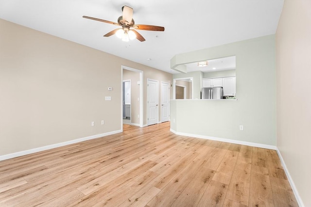 unfurnished living room with a ceiling fan, light wood-style floors, and baseboards