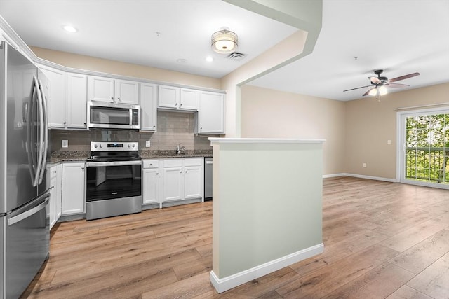 kitchen featuring appliances with stainless steel finishes, decorative backsplash, light wood finished floors, ceiling fan, and baseboards