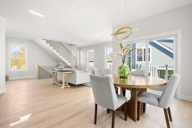 dining space with plenty of natural light, light wood-style flooring, stairway, and baseboards