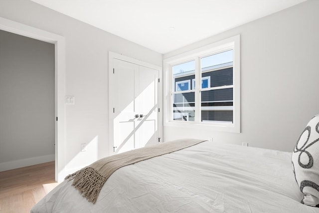 bedroom with wood finished floors, baseboards, and a closet