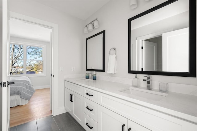 full bath featuring baseboards, double vanity, and tile patterned flooring