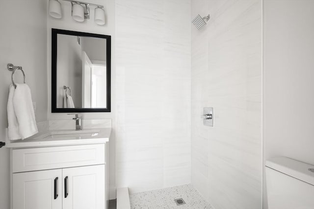 bathroom featuring tiled shower, vanity, and toilet