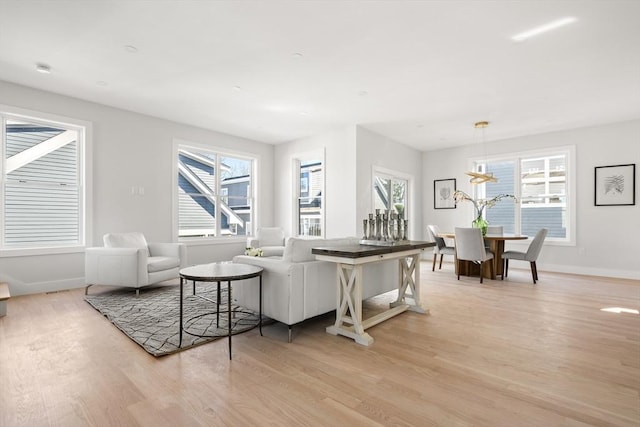 living room with light wood-style flooring, baseboards, and a chandelier