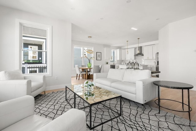 living area with light wood-style floors, baseboards, and a chandelier