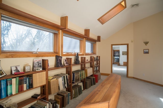 interior space featuring lofted ceiling with skylight, light carpet, and plenty of natural light