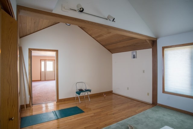 spare room featuring vaulted ceiling with beams and light wood-type flooring