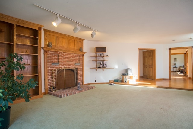 unfurnished living room with a fireplace, light colored carpet, and track lighting