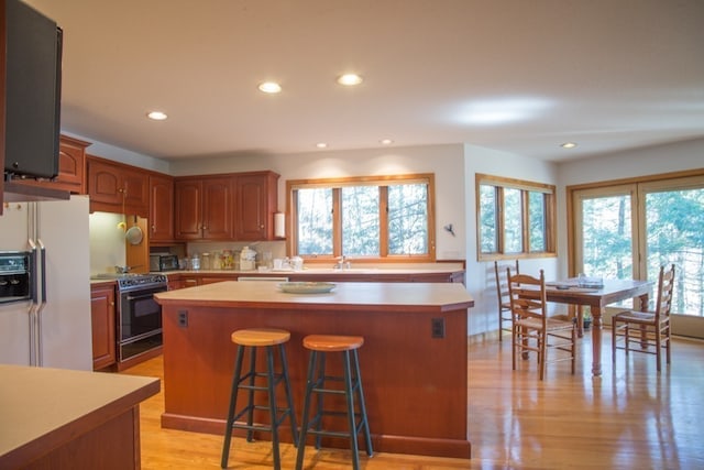 kitchen with a center island, light hardwood / wood-style floors, black appliances, and a healthy amount of sunlight