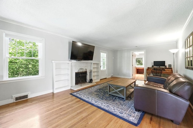 2 Silverwood Ter, South Hadley, MA 01075 - living area with a textured ceiling, wood finished floors, a fireplace with raised hearth, baseboards, and crown molding