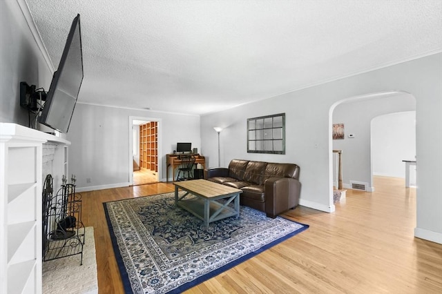 2 Silverwood Ter, South Hadley, MA 01075 - living area featuring wood finished floors, arched walkways, a brick fireplace, crown molding, and a textured ceiling