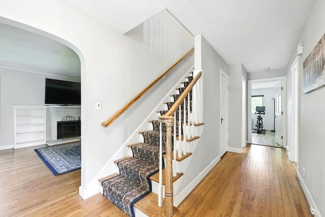 2 Silverwood Ter, South Hadley, MA 01075 - stairs featuring wood finished floors, arched walkways, baseboards, and a fireplace with raised hearth