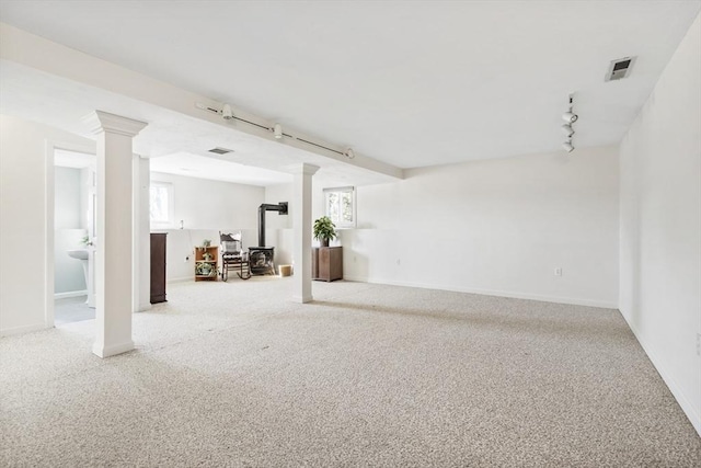 basement with light carpet, track lighting, and a wood stove