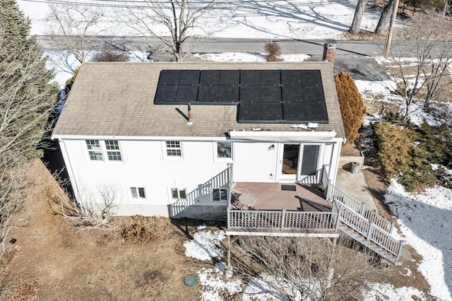 snow covered back of property with solar panels