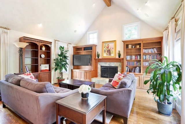 living room with wood finished floors, beamed ceiling, a fireplace, and high vaulted ceiling