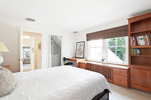 bedroom with visible vents, light carpet, radiator, and built in study area