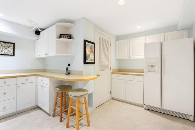 kitchen featuring white cabinetry, light countertops, and white fridge with ice dispenser