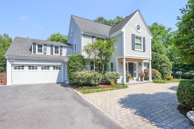 view of front facade with a garage, driveway, and a shingled roof